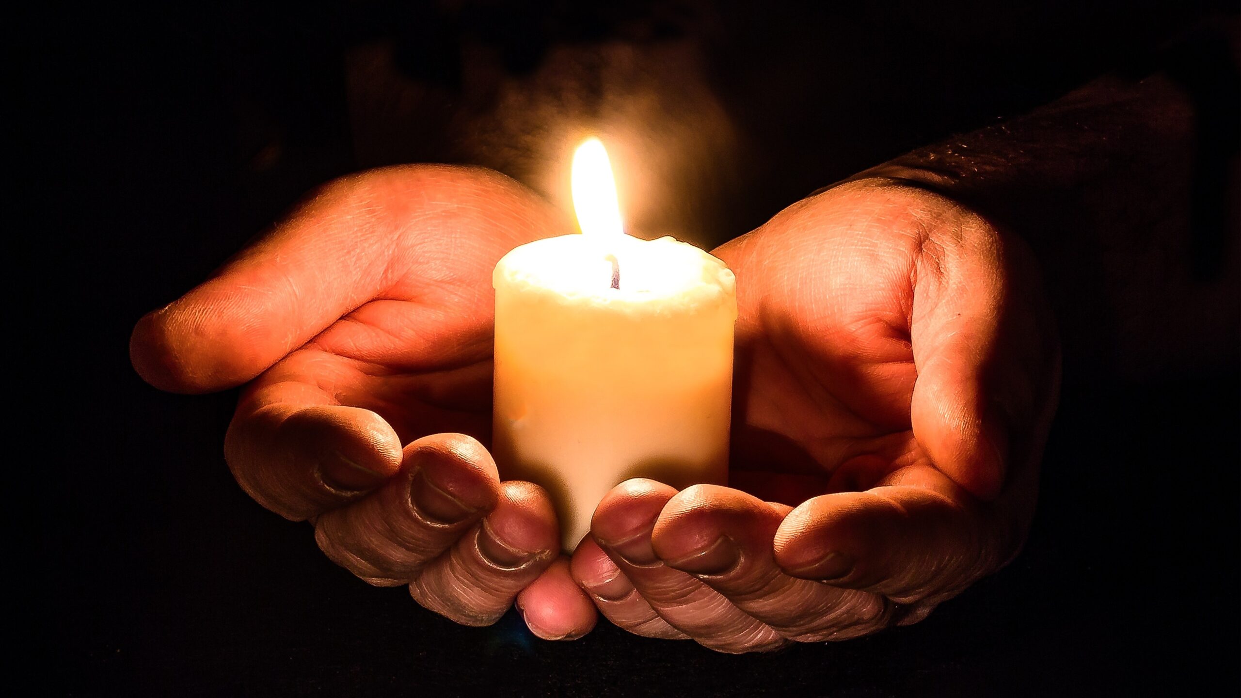 Hands gently cupped around a candle flame
